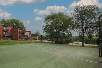 a tennis court with trees and buildings in the background